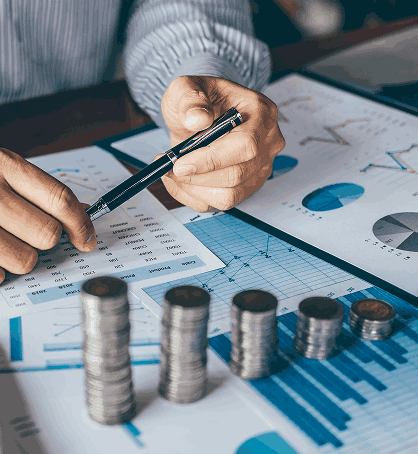 Finanzdokumente, Diagramme und Münzstapel – symbolisch für Vermögensplanung